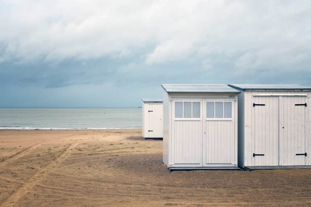 beautiful-shot-white-small-rooms-beach-shore-near-water-cloudy-sky